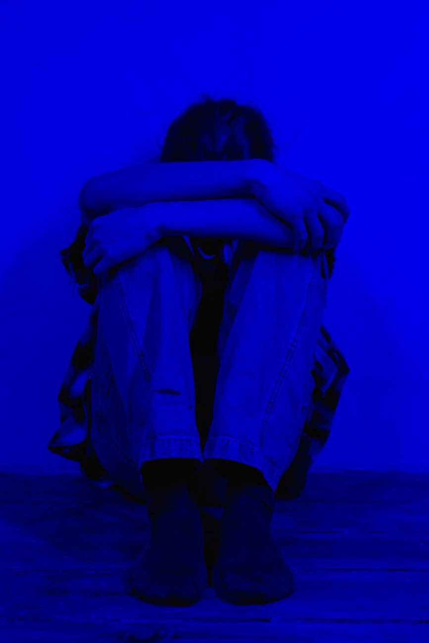 person sitting on floor with arms around knees