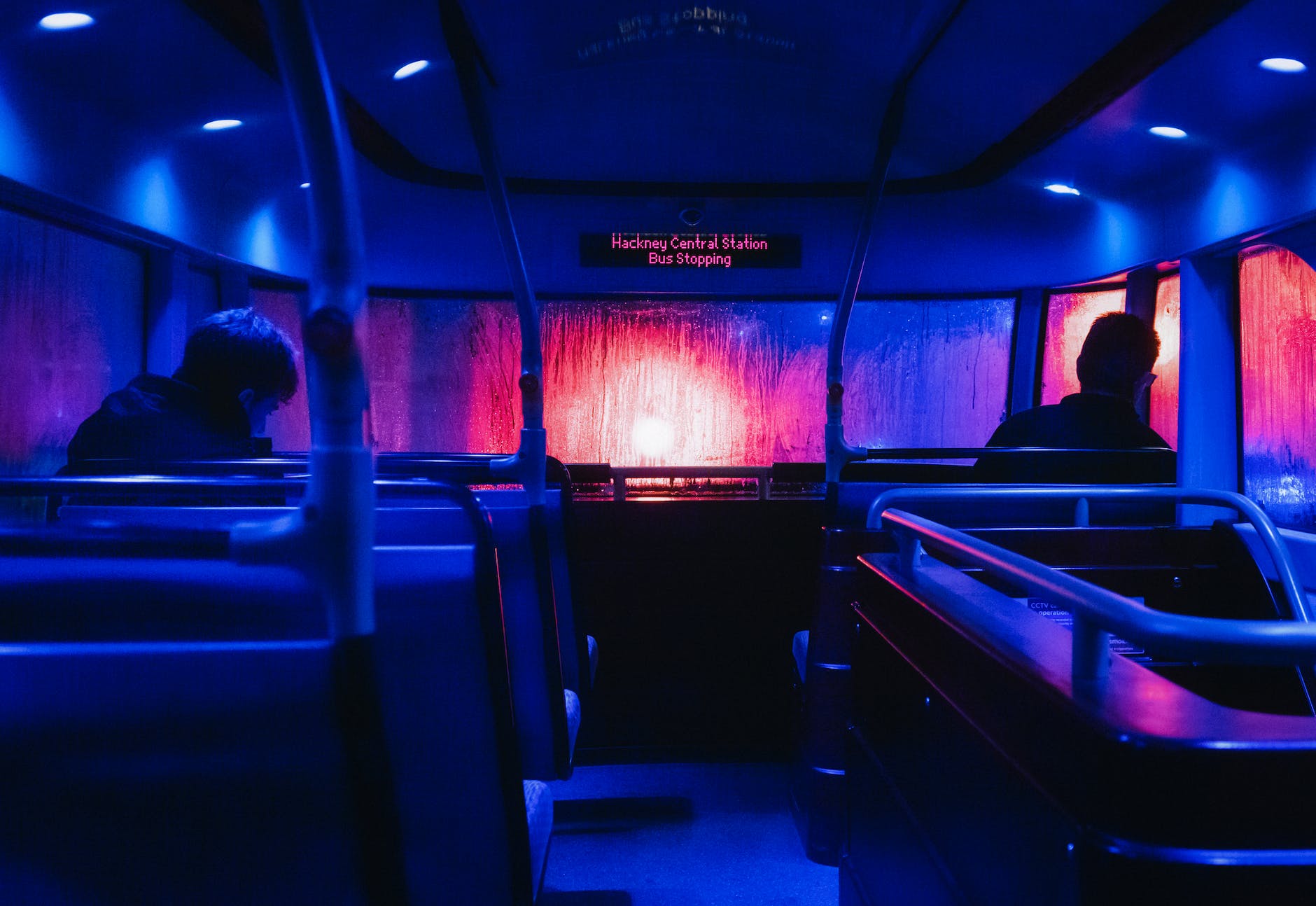 passengers on the upper deck of a double decker bus on a rainy night