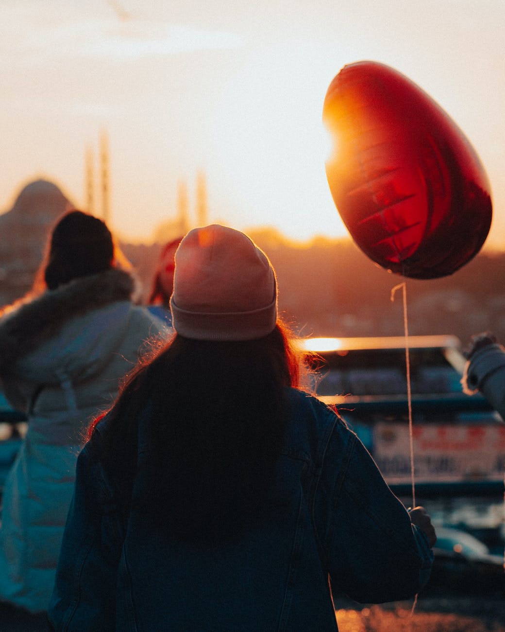 friends holding balloons during sunset