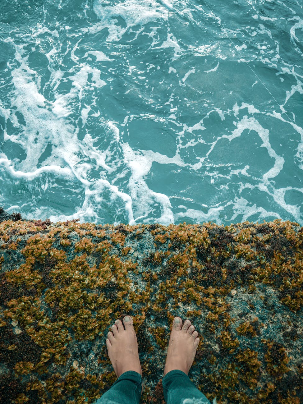person standing on cliff overlooking body of water